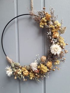 a wreath is hanging on the door with dried flowers and plants in it's center