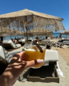 a person holding up a drink on the beach