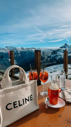 a white bag sitting on top of a wooden table next to wine glasses and bottles