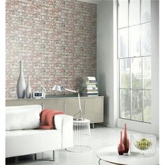 a living room with white furniture and brick wall