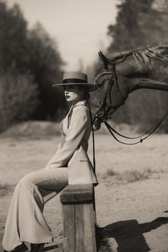 a woman sitting on a post next to a horse