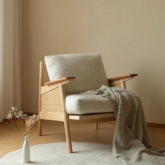 a chair sitting on top of a wooden floor next to a vase filled with flowers