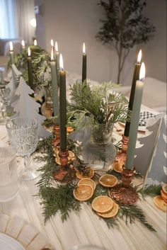 the table is set with candles, orange slices and pine cones on it's centerpiece