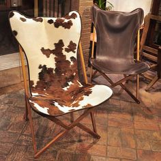 two brown and white chairs sitting next to each other on a brick floor in front of a fireplace