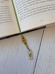 an open book with a green string attached to it and a yellow flower on the end