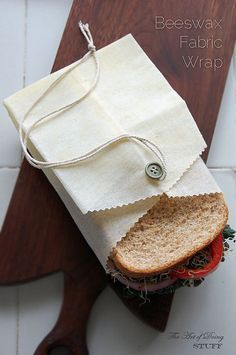 a sandwich wrapped in paper on top of a cutting board