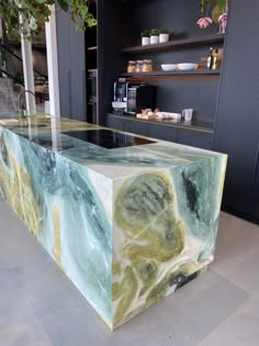 a counter made out of marble with green and yellow designs on the top, in front of a black wall