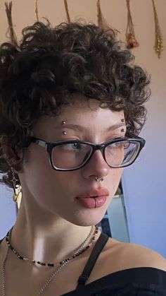 a close up of a person wearing glasses and a necklace with dangling beads on it