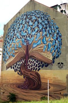 a painting on the side of a building with a tree growing out of an open book