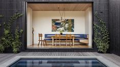 an outdoor dining area with table and chairs next to a swimming pool in the backyard