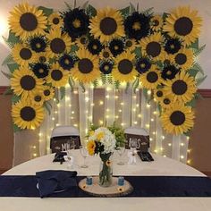 a table with sunflowers on the wall and decorations around it for a wedding reception