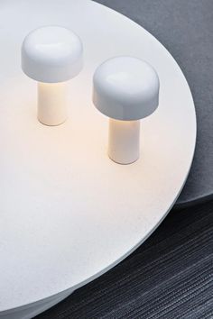 two white table lamps sitting on top of a white plate next to a gray wall