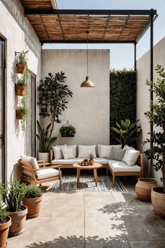 an outdoor living area with potted plants and couches on the side of the building