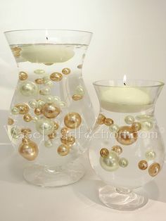 two glass vases with pearls on them and a lit candle in the middle one