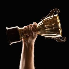 a man holding up a trophy in the air with his hand on top of it