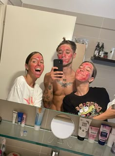 three people with their faces painted in the mirror