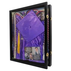 a purple graduation cap and tassels are in a black shadow box on a white background