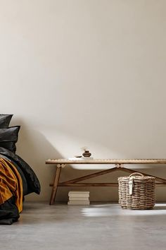 a bed with black and yellow sheets in a room next to a wooden bench on the floor