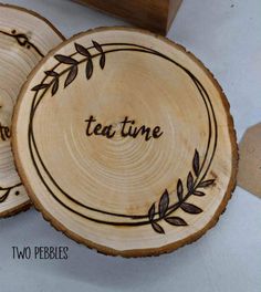 two wooden coasters with the words tea time engraved on them, sitting next to each other