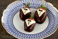 four chocolate covered strawberries on a blue and white plate