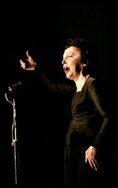 a woman standing in front of a microphone with her hands out to the side,