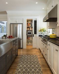 a kitchen with white cabinets and stainless steel appliances, along with a rug on the floor