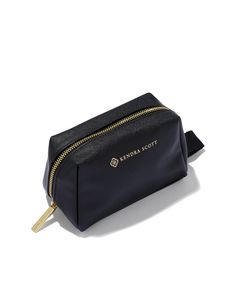 a black cosmetic bag with gold zippers on the front and side, sitting on a white surface