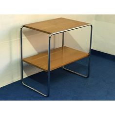 a wooden table sitting on top of a blue carpeted floor next to a white wall