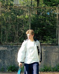 a young man holding a tennis racquet on top of a tennis ball court