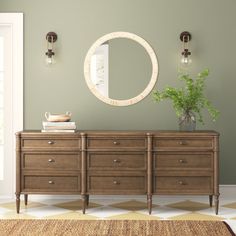 a room with a dresser, mirror and potted plant on the table in front of it