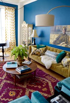 a living room filled with furniture and a painting on the wall above it's coffee table