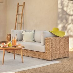 a wicker couch sitting on top of a rug next to a table with drinks