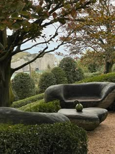 an outdoor seating area in the middle of a park with trees and bushes around it