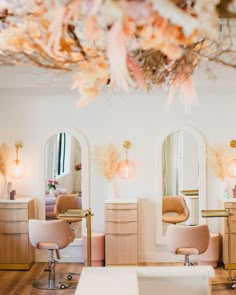 a hair salon with chairs, mirrors and flowers hanging from the ceiling in front of it