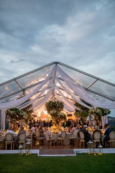 an outdoor tent set up with tables and chairs under the canopy for a wedding reception