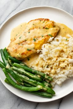 chicken, rice and asparagus on a plate with gravy over it