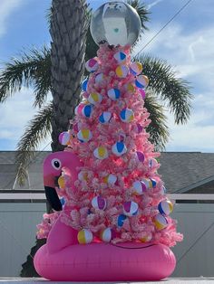 a pink christmas tree sitting next to a palm tree