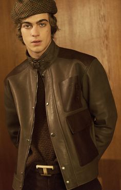 a young man wearing a leather jacket and hat