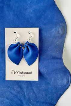 Why not add a dash of elegance with our Handcrafted Bow-Shaped Leather Earrings? Crafted from soft leather in a captivating royal blue hue, they're perfect for making a statement. Treat yourself or someone special today! #HandmadeEarrings #BowShape #BlueLeather #Leatherearrings #Earrings #handmadejewellery #uniqueearrings #oneofakindjewelry #statementjewelry #shoppingonline Petal Earrings, Royal Blue Dress, Earring Crafts, Ear Jewelry, Unique Charms, Leather Earrings, Blue Hues, Unique Earrings, Blue Leather