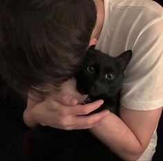 a person holding a black cat in their arms