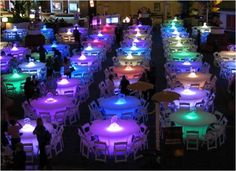 many tables and chairs are lit up with colored lights