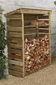 a pile of wood sitting in front of a wooden shed next to a planter