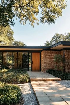 the exterior of a modern house with brick walls and doors, surrounded by graveled walkways