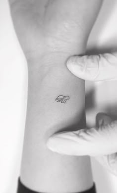 a woman's wrist tattoo with a small butterfly on it, in black and white