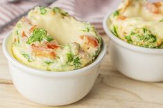 two white bowls filled with food on top of a wooden table