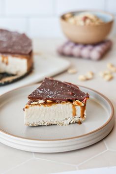 two pieces of dessert sitting on top of a white plate next to a bowl of nuts