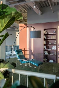 a blue chair sitting in the middle of a room next to a book shelf filled with books