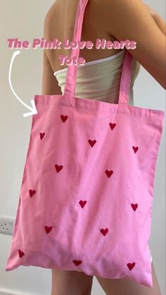 a woman holding a pink bag with hearts on it and the words, the pink love heart