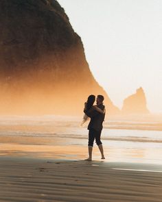 a man carrying a woman on his back while standing on the beach near the ocean