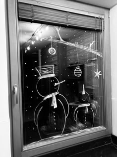 a black and white photo of two snowmen in a window